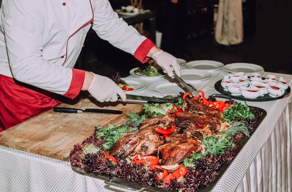 chef prepares a meat dish with vegetables on the table in a restaurant