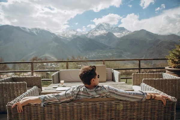 man sits in a restaurant on the terrace overlooking the beautiful mountains