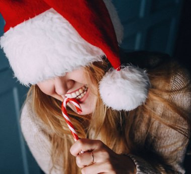 Kız santa claus şapka ve kırmızı-beyaz çizgili şenlikli şeker ile