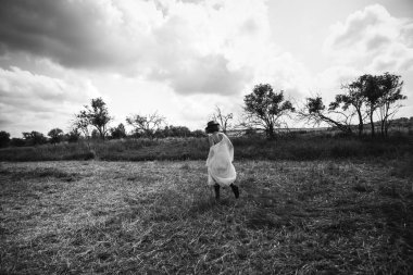 köyden kız boyunca beyaz bir elbise sahte alanına yürüyor ve şapka keçilere gider