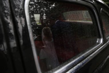 Gelin ve damat yağmur altında bir retro otomobil cam yansıması