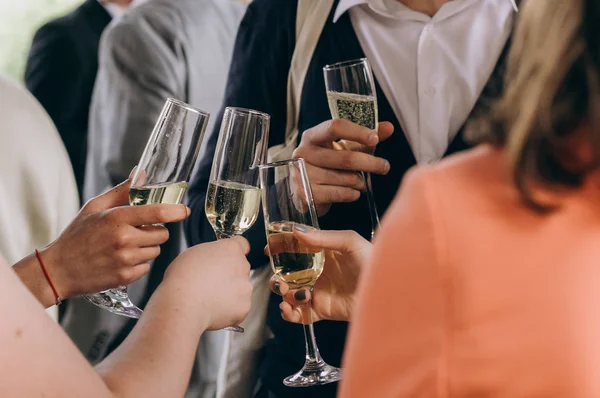 company of friends with glasses of champagne close hands at a party