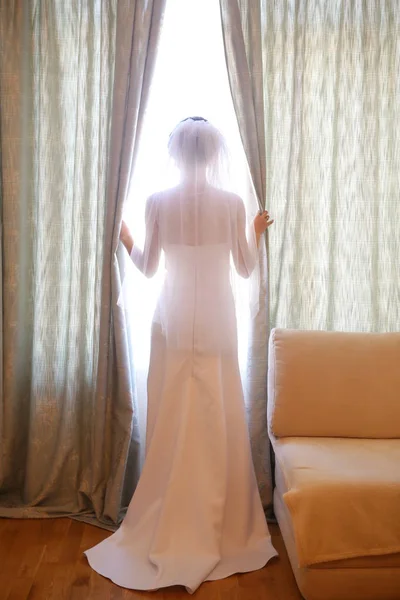 新娘在白色的礼服和面纱里面在窗口附近的房间 — 图库照片