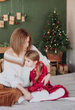kız bir Bordo elbise ve anne rustik bir odada bir Noel ağacı süsle
