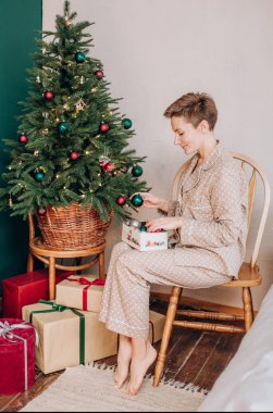 pijama kutlama kız bir kadeh şampanya ile hediye kutuları dekor Noel ağacı Noel