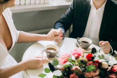 Çift el ele tutuşarak bir masada bir kafede oturan aşık