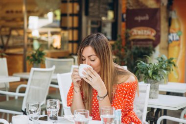 bir masada kahve içme dışında bir kafede esmer kız