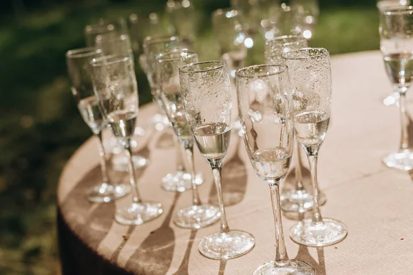 许多杯香槟酒在外面的桌子上 在雨中滴水 — 图库照片