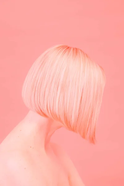 silhouette of a woman with a short haircut in a coral background