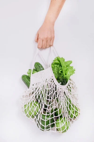 hand holds eco bag mesh vegetables fruits