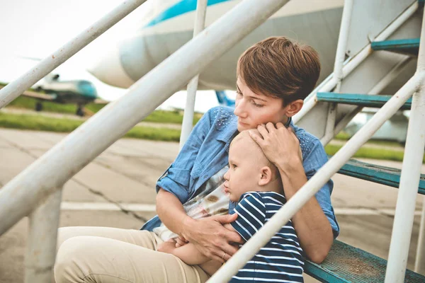 Mother hugging baby airplane outside season summer — Stock Photo, Image