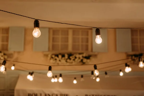 Лампочки ретро гирлянда за стеной дома — стоковое фото