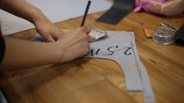 Terzi kadın atölyede içi boş desenler kesiyor.