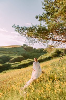 Dışarıda kanatları olan beyaz elbiseli kadın özgürlüğe doğru koşuyor.