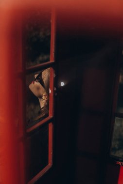Kırmızı retro telefon kulübesinde güneş gözlüklü moda kızı.