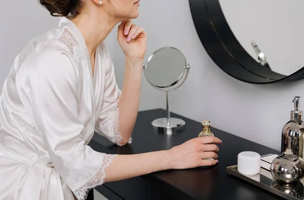 woman in silk robe in front of dressing room mirror with accessories