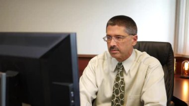 Adam bir masaüstü bilgisayar, ofisinde bir rapor okuma