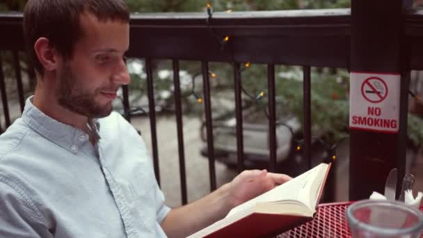 Man Reads Funny Novel Balcony Populated Urban City Area — Stock Video