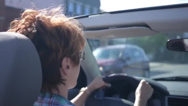 女性は小さな町を通ってコンバーチブル車を運転 後部座席から撮影 — ストック動画