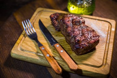 Çatal ve bıçak otlar baharatlar ve tuz ahşap tahta üzerinde sulu orta dana kaburga eti.