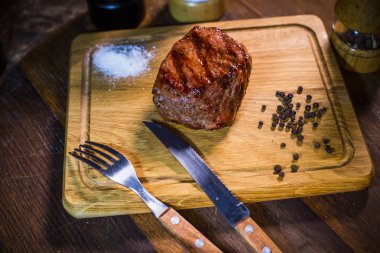 Ahşap tahta çatal ve bıçak otlar baharatlar ve tuz ile sığır eti biftek