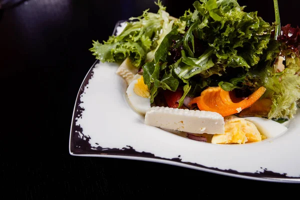 Salade met ei, rode peper, kaas en tomaat geserveerd op een bord. — Stockfoto