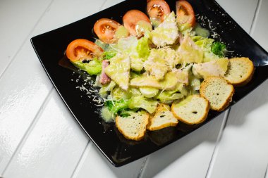 Bir beyaz tahta üzerinde siyah plaka Sezar salatası jambon ve Bıldırcın yumurta