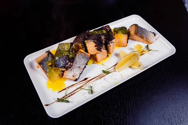 Zlato prosklený filet lososa s plátky pomeranče, koření a bazalka na bílém štítku na tmavém pozadí. — Stock fotografie