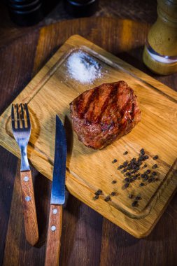 Çatal ve bıçak Otlar baharatlar ve SA ile ahşap tahta üzerinde sığır biftek