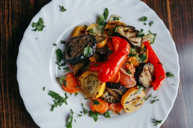 ahşap bir masa üzerinde beyaz bir tabak üzerinde ızgara sebze