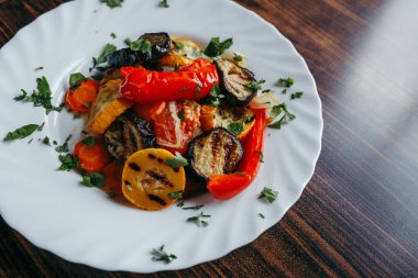 ahşap bir masa üzerinde beyaz bir tabak üzerinde ızgara sebze