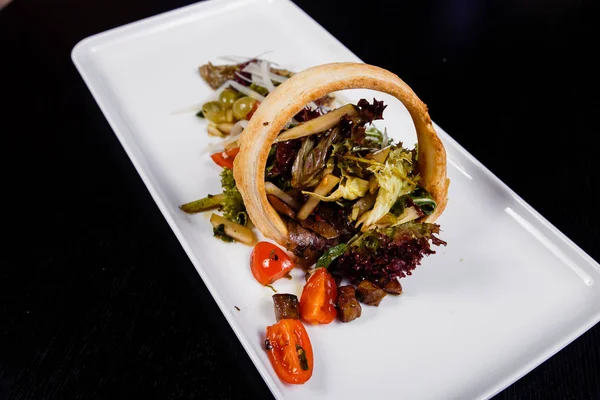 Salada com carne defumada, salsichas, queijo, uvas, tomate cereja, azeitonas, folhas de manjericão, rúcula e tomate seco — Fotografia de Stock