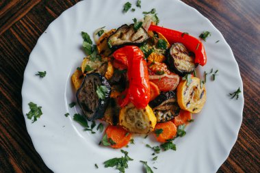 ahşap bir masa üzerinde beyaz bir tabak üzerinde ızgara sebze