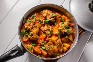 Bir kazan üzerinde domates soslu patates dolması etli