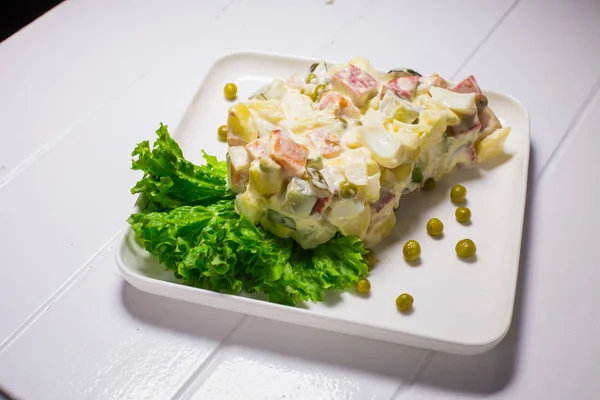 Salat mit Erbsen, Mayonnaise, Kartoffeln, Wurst, Kohl, Karotten und Eiern — Stockfoto