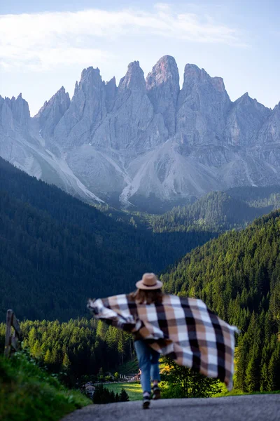 Şapkalı ve pançolu kız dolomitlerle yürüyor.