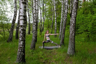 Kız dışarıda, ormanda yoga yapıyor.