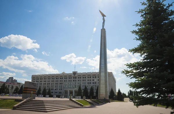 Monumen kemuliaan dalam bentuk prasasti dengan seorang pria dengan sayap di tangan dan bangunan pemerintah di Samara, Rusia. Pada hari musim panas Sunny. 19 Juni 2018 — Stok Foto