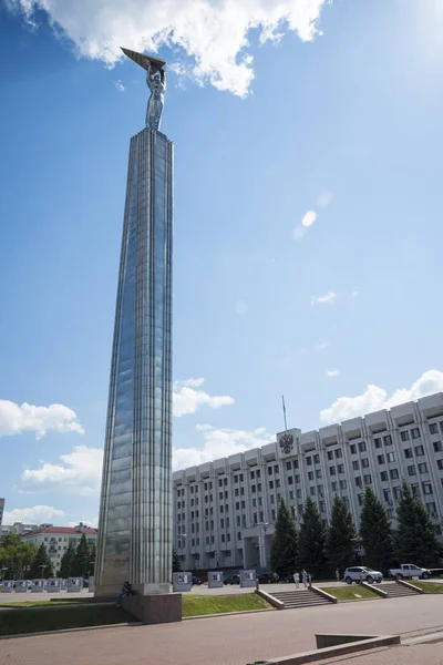 Monumen kemuliaan dalam bentuk prasasti dengan seorang pria dengan sayap di tangan dan bangunan pemerintah di Samara, Rusia. Pada hari musim panas Sunny. 19 Juni 2018 — Stok Foto