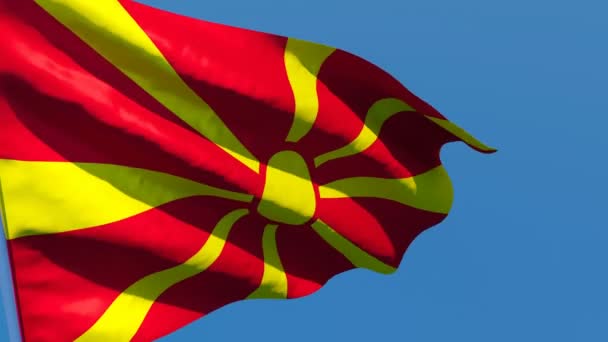 Державний прапор Македонії коливається вітром проти блакитного неба. — стокове відео