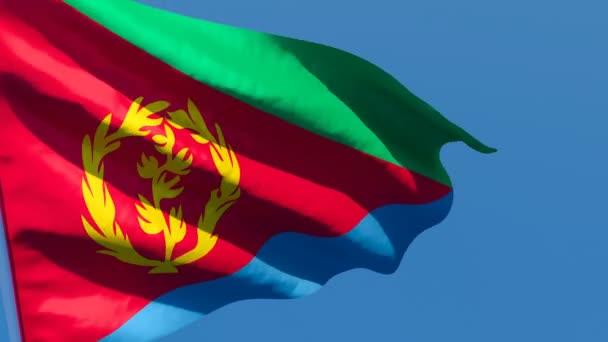 Державний прапор Еритреї пурхає вітром проти блакитного неба. — стокове відео
