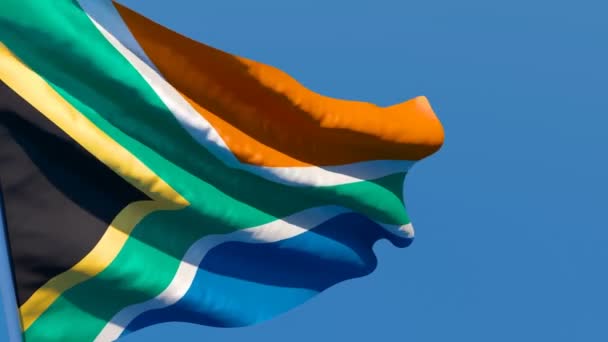 La bandera nacional de Sudáfrica ondea en el viento contra un cielo azul — Vídeos de Stock