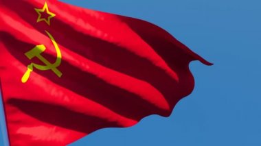 SSCB bayrağı mavi gökyüzüne karşı rüzgarda dalgalanıyor.