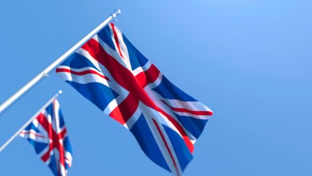 La bandera nacional de los aleteos británicos en el viento contra un cielo azul — Vídeos de Stock