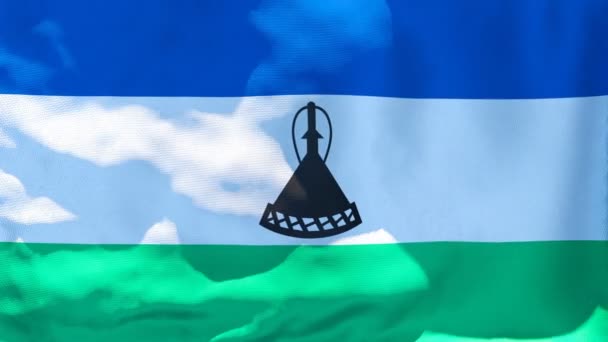 Die Nationalflagge Lesothos flattert im Wind vor blauem Himmel — Stockvideo