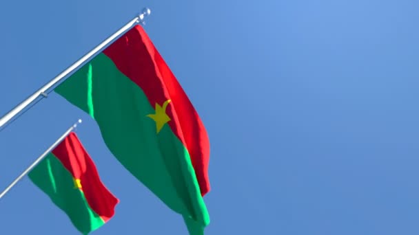 La bandera nacional de Burkina Faso ondea en el viento contra un cielo azul — Vídeo de stock