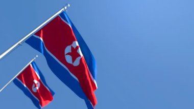 Kuzey Kore 'nin ulusal bayrağı mavi gökyüzüne karşı rüzgarda dalgalanıyor.