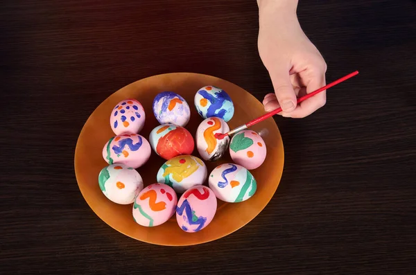 Girl paints Easter eggs. hand, brush and paint on the table. pre — Stock Photo, Image