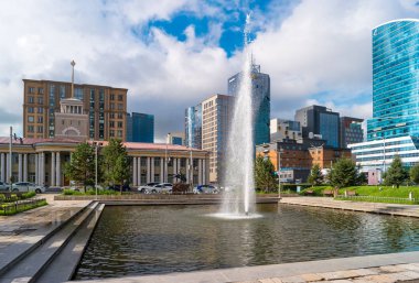 Ulan Batur, Moğolistan - 8 Ağustos 2018: Görünümü otel mavi gökyüzünde Ulaanbaatar Merkezi ve modern binalar. Şehir meydanında fıskiye.