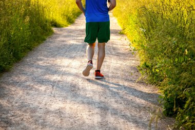 Erkek sporcu sahada yolda koşuyor..